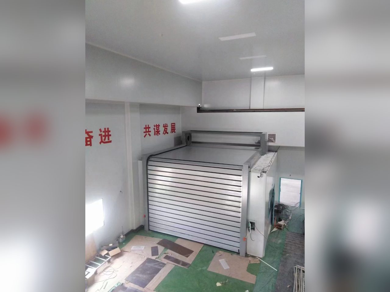 打磨房内银灰色铝合金硬质涡轮快速门L型安装，竖向门板经顶部90°转向与水平段相连实拍